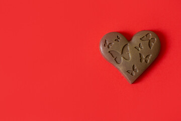 Heart shaped chocolate with butterflies on a red background. Chocolate heart for Valentine's Day