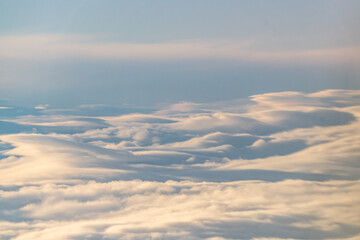 Calming and serene clouds from above with slight sunshine tones on the tops. Heavenly shining cloud in the sky background, wallpaper, wall art beautiful.
