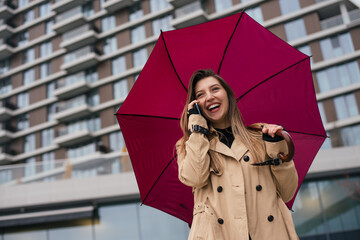 Smiling business woman standing under umbrella