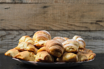 Homemade cookies in the form of bagels with jam filling sprinkled with powdered sugar on a wooden background.