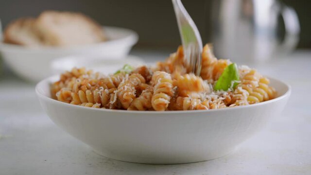 Someone eat fusilli pasta with tomato sauce, roasted eggplant and parmesan cheese