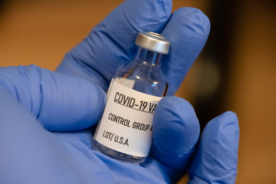 Covid 19 Vaccine Bottle Is Being Held By A Hand With A Blue Latex Glove