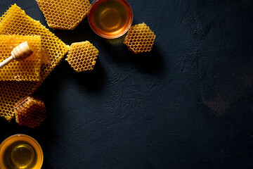 Honey with honeycomb on black table, top view. space for text