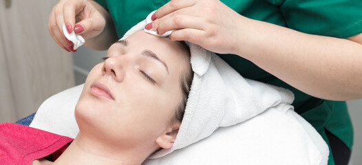 Fototapeta na wymiar Face skin care. Beautician applying beauty oil mask on face using brush In spa salon