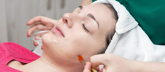 Obraz na płótnie Canvas Face skin care. Beautician applying beauty oil mask on face using brush In spa salon