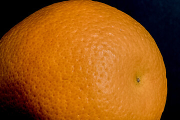Close up, macro shot of the skin of a orange fruit with pores, indents in the tangerine skin color...