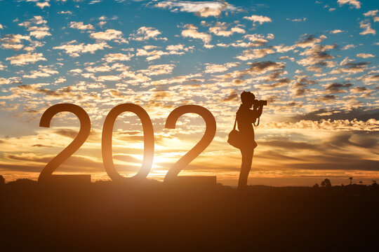 Silhouette of photographer taking photos in 2021 years at sunrise or sunset background, with copy space. Idea for happy new year 2021.