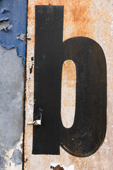 Old brush lettered letter "b" on a grungy peeling painted wall, vertical
