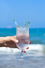 Glass of fresh clear cold water with ice and blue ocean on the background. Healthy lifestyle. Glass of water with water drops.