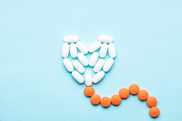 heart symbol formed white pills or tablets isolated on a blue background. above view. outer space. cardiac medicine concept