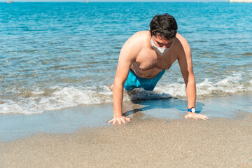 Fototapeta na wymiar Hispanic man with a mask working out on the beach
