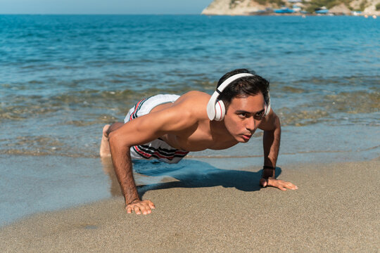 Outdoor photo of a sporty man with headphones, working out. Exercise at sea