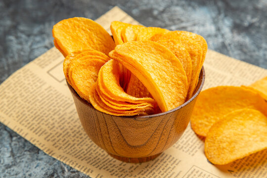 High resolution photo of delicious homemade chips on newspaper on gray background