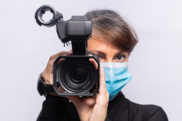 cinegrafista usando máscara de proteção contra coronavírus com câmera de filmar com o foco seletivo na lente