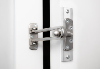 Door lock guard installed. The white door is open. Hinged bar lock or security door guard. Home...