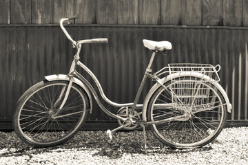 Fototapeta na wymiar Vintage cruiser bicycle with bike stand and rear carrier against a wooden fence.