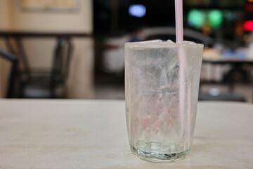 Glass of iced water with straw at restaurant