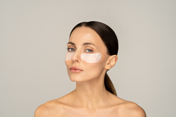 Woman applying hydrogel under-eye recovery patches enriched with collagen, vitamin E, provides...