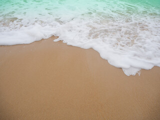 Sand beach with white sea soft wave on top view for assembling an article about travel in summer holiday or ocean coast nature.
