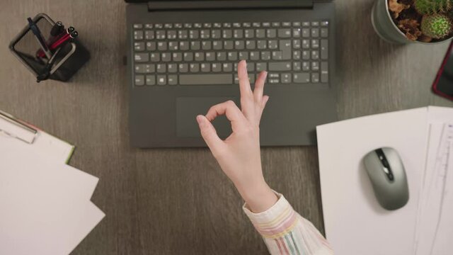 OK Hand Gesture Over Workspace With Laptop, Mouse, And Pen Holder - top view, slow motion