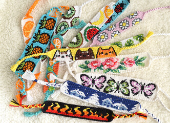 Woven DIY friendship bracelets handmade of embroidery floss with knots, alpha patterns