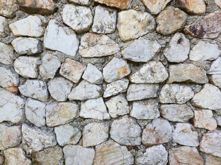Gray-white stone and granite - of various sizes, arranged neatly as a wall or fence. wall composes of various size of stone
