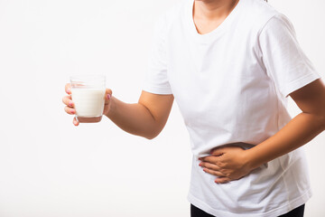 Closeup young woman intolerant use hand holding glass milk she is bad stomach ache she has bad lactose intolerance unhealthy problem with dairy food products, studio shot isolated on white background