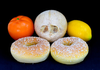 Yummy yellow donut, orange tangerine, yellow lemon and white coconut, isolated on black background.