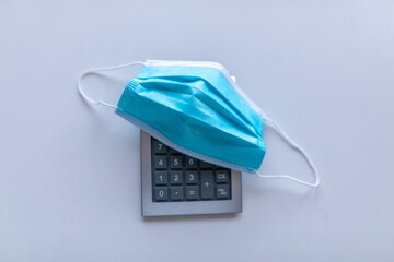 Calculator and face mask pandemic disease covid19 coronavirus global financial crisis concept