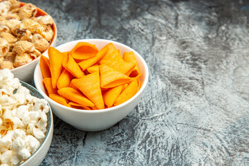 front view different snacks for movie time on a light-dark background cips rusks popcorn