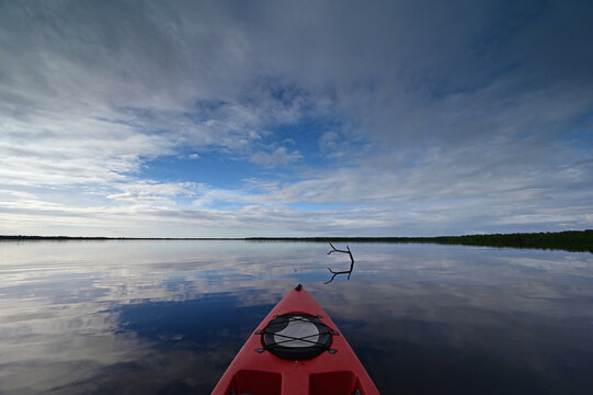 Red kayak on Coot Bay in Everglades National Park, Florida under winter cloudscape reflected in tranquil water,