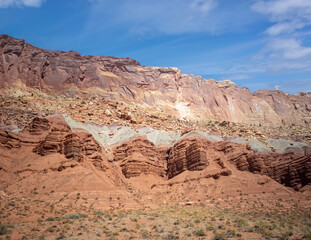Fototapeta na wymiar Sublime monoliths and towering sandstone cliffs on a hot partly cloudy summer day at Capitol Reef National Park in Southern Utah.