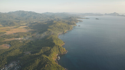 Mist over green mountains at ocean coast aerial. Philippines countryside with buildings, houses, cottages at palm trees. Nobody nature seascape and landscape of El Nido Island, Visayas Archipelago
