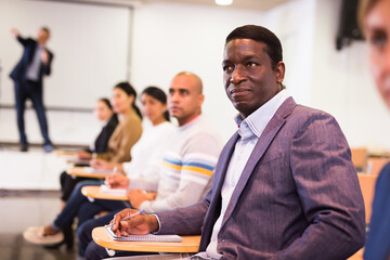 Focused African American attentively listening to lecture with colleagues at conference