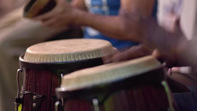Close-up on people playing bongos and other ethnic instruments