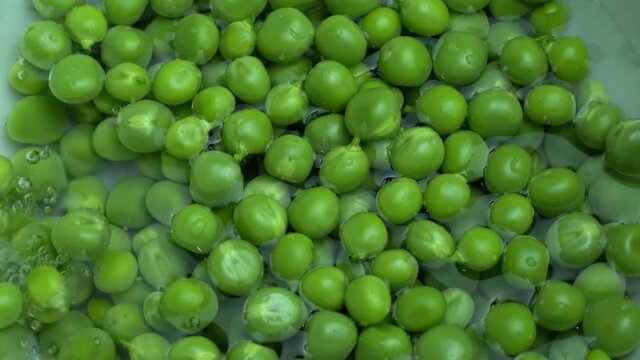 4k pouring water in Green fresh Peas closeup