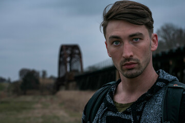 Young Man Moody Portrait with Train Tracks in Background