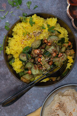 Vegan millet and spicy zucchini in black bowl with chapati on gray table