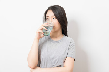Beautiful portrait young asian woman smiling drinking a glass of water mineral on white background.