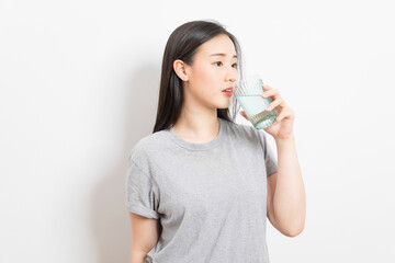 Beautiful portrait young asian woman smiling drinking a glass of water mineral on white background.