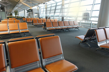 Empty chairs in airport terminal waiting area with sunlight in the outdoor.