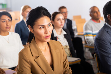 Fototapeta premium Portrait of asian woman attending business training, listening with interest to speaker