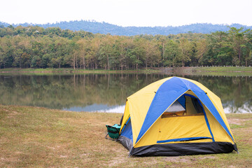 Tent on green grass beside lake.