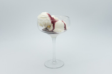 Vanilla ice cream with honeysuckle or blueberry syrup in glass on white background. 