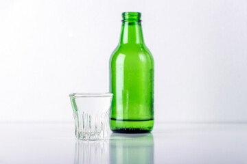 Bottle and glass with soju on white table. Traditional korean alcoholic beverage