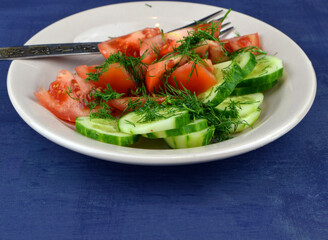 
salad of cucumbers and fresh tomatoes lies in a plate on the table