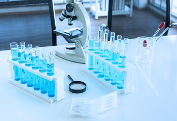 Scientific equipment on lap table such as microscope ,beaker, test tube with blue fluid , pipet and magnifying glass