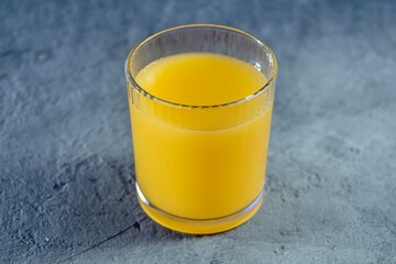 Glass with yellow lemon juice on gray background. Colors of Year 2021. Yellow-graym