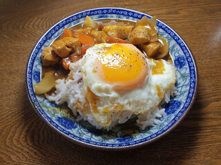Japanese curry rice with chicken meat, egg, onion, carrot and potato close-up on a plate.