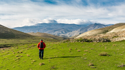 Fototapeta na wymiar A traveler with a backpack walks in a mountain valley